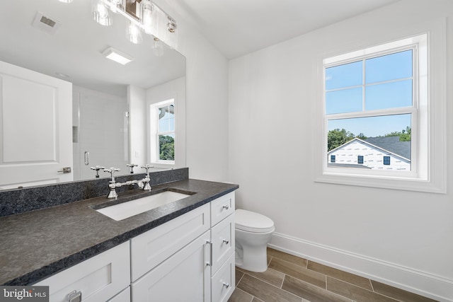 bathroom featuring vanity, toilet, and a shower with shower door