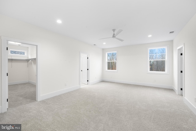 unfurnished bedroom with a spacious closet, a closet, ceiling fan, and light colored carpet