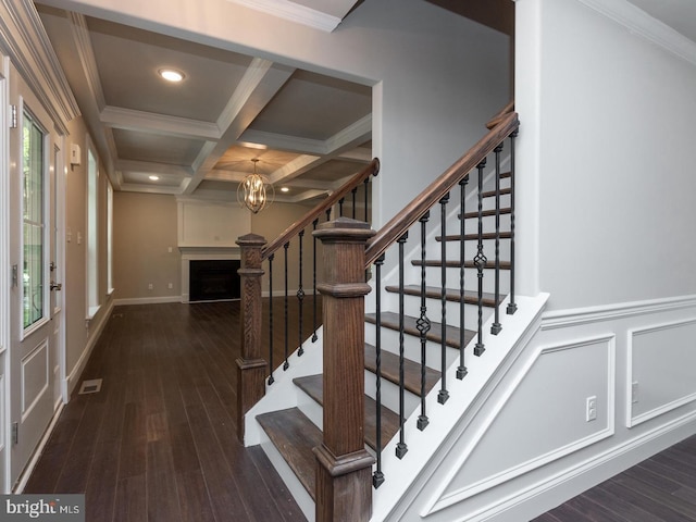 stairs with ornamental molding, coffered ceiling, wood finished floors, and beamed ceiling