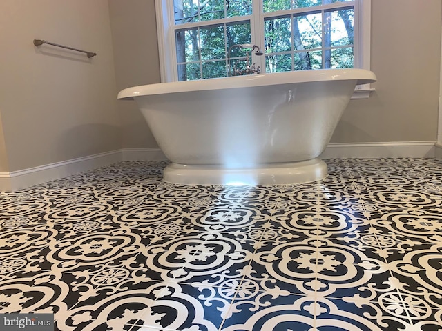 bathroom featuring baseboards, a freestanding tub, and tile patterned floors