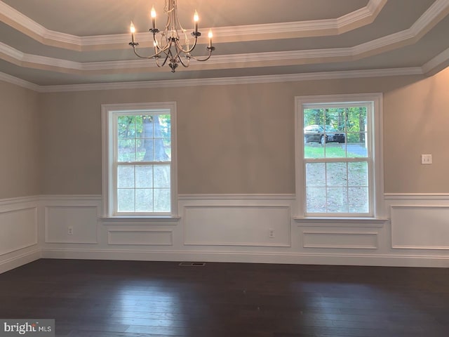 empty room with a tray ceiling, a wainscoted wall, a notable chandelier, and dark wood finished floors