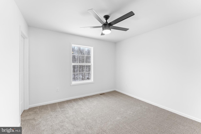 carpeted spare room featuring visible vents, a ceiling fan, and baseboards