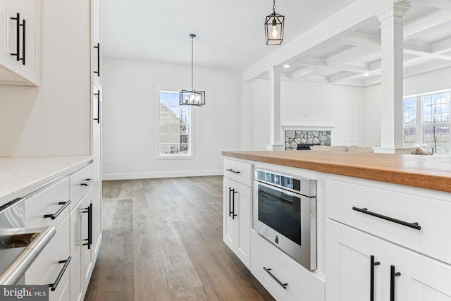 kitchen featuring light countertops, coffered ceiling, decorative light fixtures, and white cabinets