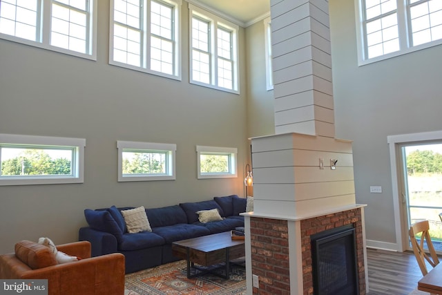 living room featuring a towering ceiling, decorative columns, a brick fireplace, and a wealth of natural light