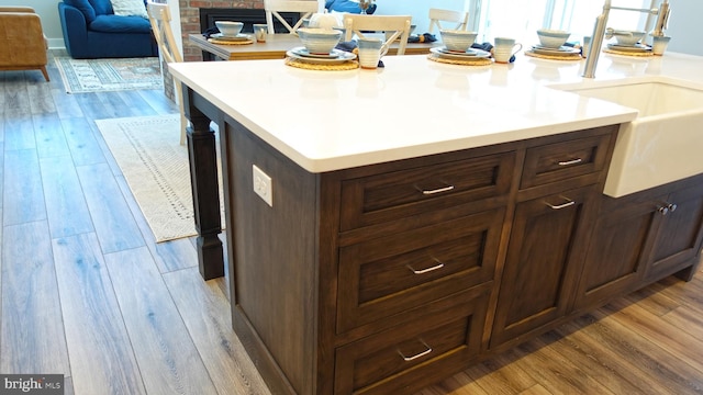 kitchen with sink, a kitchen island, dark brown cabinets, and light wood-type flooring