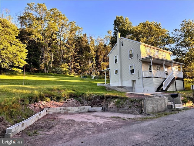 view of side of home featuring a yard and a balcony