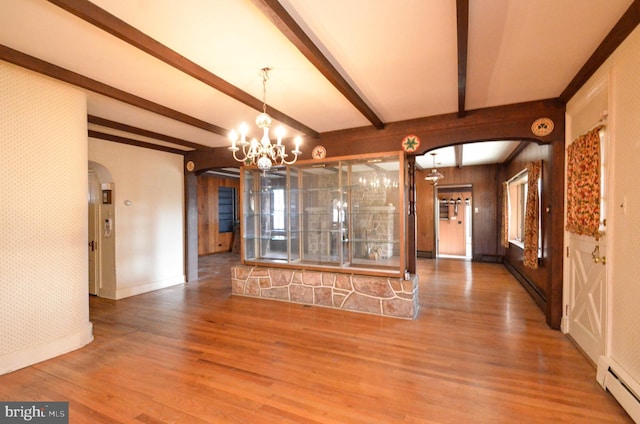 unfurnished living room featuring a chandelier, beam ceiling, a baseboard radiator, and hardwood / wood-style flooring