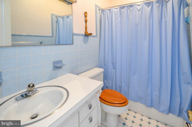 full bathroom with shower / bathtub combination with curtain, vanity, tile walls, and toilet