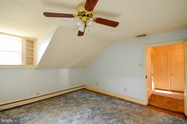 additional living space featuring built in shelves, ceiling fan, a baseboard radiator, and lofted ceiling