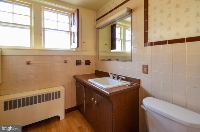 bathroom with vanity, toilet, tile walls, and radiator