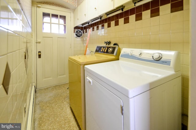 clothes washing area featuring washing machine and dryer, cabinets, and a baseboard heating unit