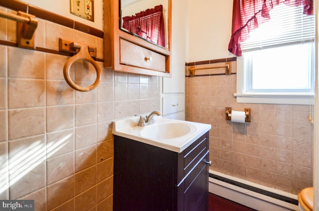 bathroom with vanity, toilet, baseboard heating, and tile walls