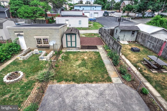 rear view of property featuring a yard, an outdoor fire pit, and a storage shed