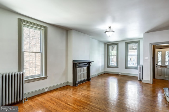 unfurnished living room featuring hardwood / wood-style floors and radiator