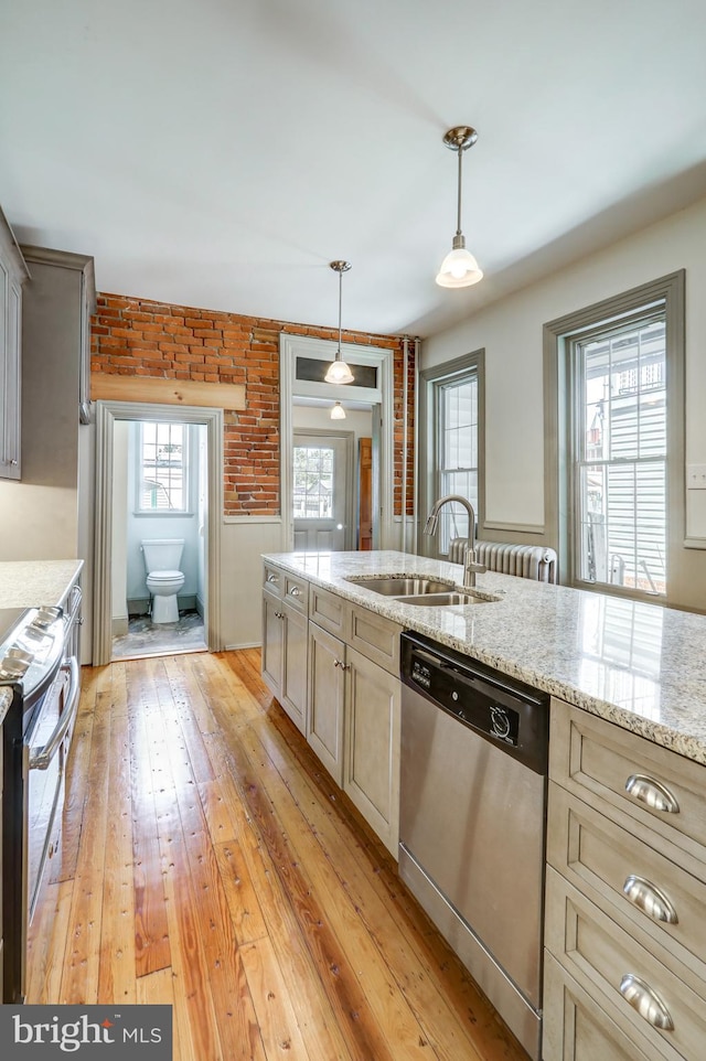 kitchen featuring light stone countertops, sink, light hardwood / wood-style floors, decorative light fixtures, and appliances with stainless steel finishes