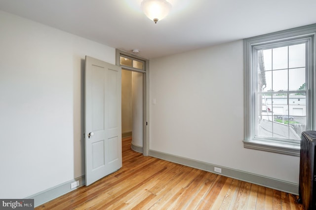 unfurnished bedroom featuring light hardwood / wood-style floors and radiator