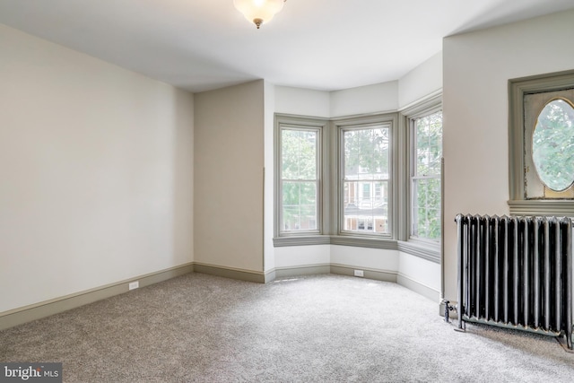 carpeted spare room with radiator heating unit and a healthy amount of sunlight