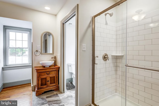 bathroom with hardwood / wood-style floors, vanity, a shower with shower door, and toilet