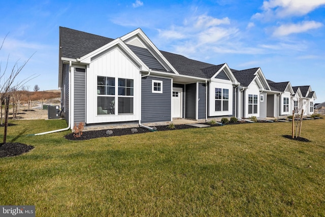 view of front facade featuring cooling unit, a shingled roof, and a front yard