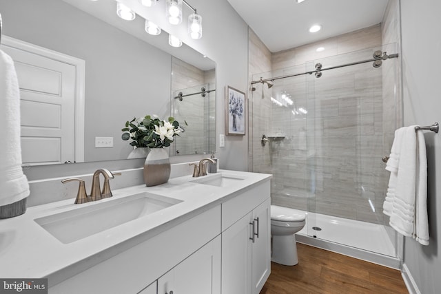 bathroom featuring vanity, toilet, wood-type flooring, and a shower with door