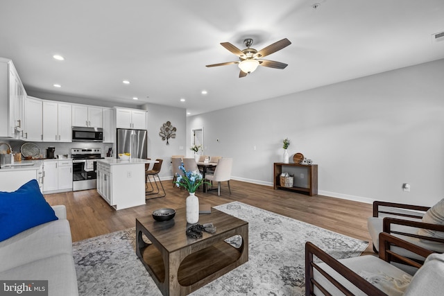 living room with wood-type flooring, sink, and ceiling fan