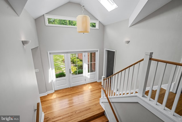 foyer with a skylight, wood-type flooring, a healthy amount of sunlight, and high vaulted ceiling