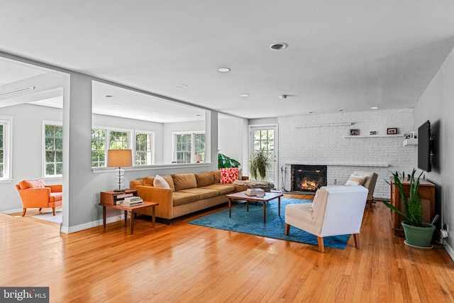 living room featuring light hardwood / wood-style floors, a brick fireplace, and brick wall