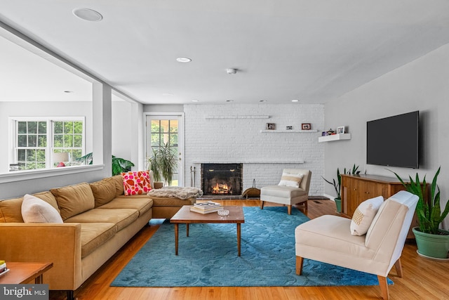 living room with brick wall, a fireplace, and hardwood / wood-style flooring