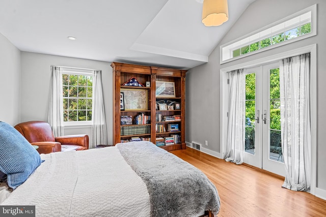 bedroom with access to outside, vaulted ceiling, french doors, and light hardwood / wood-style flooring