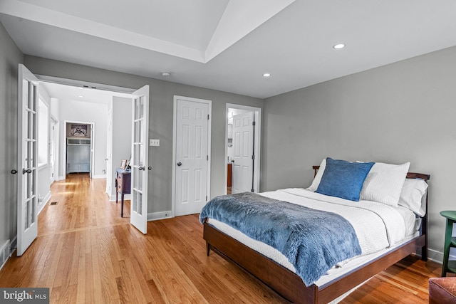 bedroom featuring french doors, light hardwood / wood-style flooring, and lofted ceiling