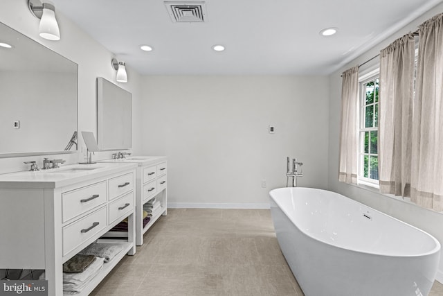 bathroom featuring a tub, a wealth of natural light, tile patterned flooring, and double sink vanity