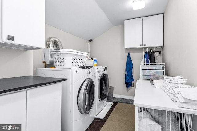 clothes washing area featuring cabinets, washer and clothes dryer, and dark carpet