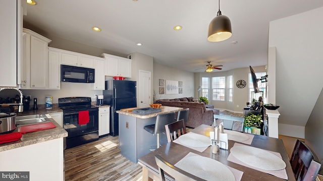 kitchen featuring sink, hanging light fixtures, a kitchen island, white cabinets, and black appliances