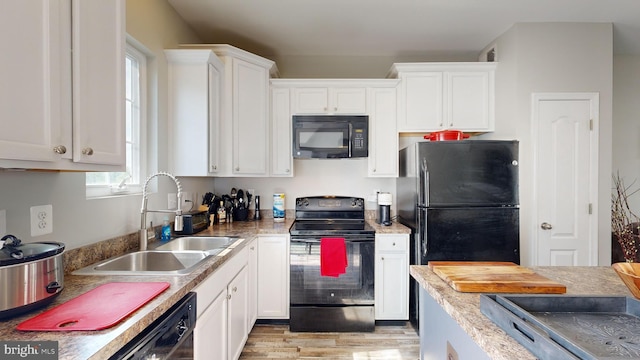 kitchen with black appliances, light hardwood / wood-style floors, white cabinets, and sink