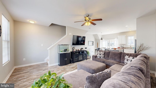 living room featuring ceiling fan, light hardwood / wood-style floors, and sink