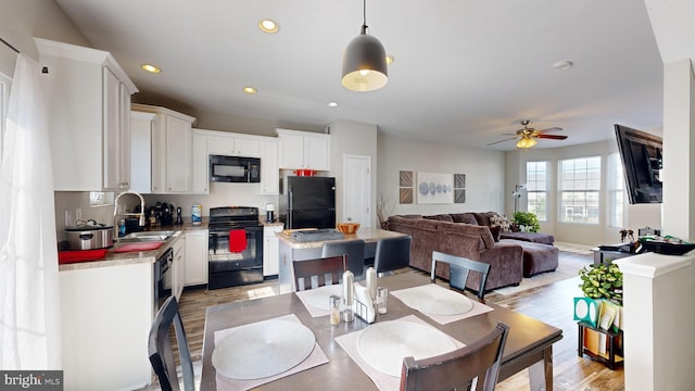 dining area with ceiling fan, light hardwood / wood-style floors, and sink