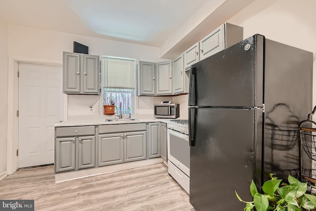 kitchen with gray cabinets, black fridge, sink, and gas range gas stove