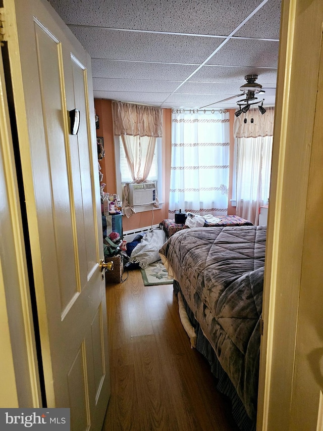 bedroom featuring hardwood / wood-style floors, cooling unit, and a drop ceiling