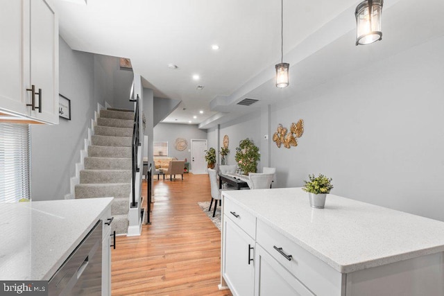 kitchen with light stone counters, decorative light fixtures, light hardwood / wood-style flooring, dishwasher, and white cabinets