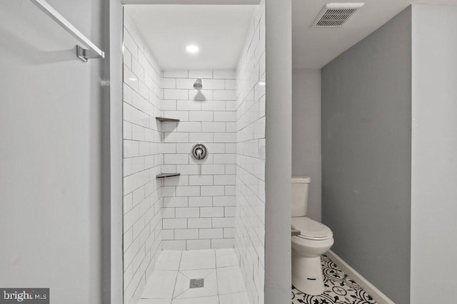 bathroom with a tile shower, tile patterned flooring, and toilet