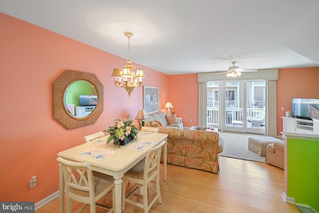 dining area with ceiling fan with notable chandelier and light hardwood / wood-style floors