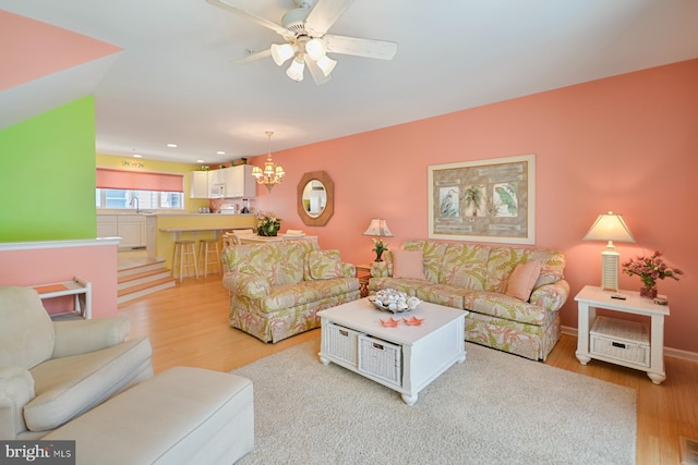 living room with sink, ceiling fan with notable chandelier, and light hardwood / wood-style floors