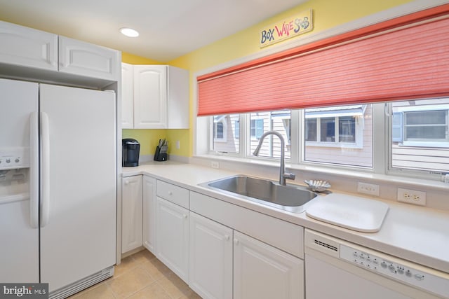 kitchen with sink, white appliances, light tile patterned floors, and white cabinets