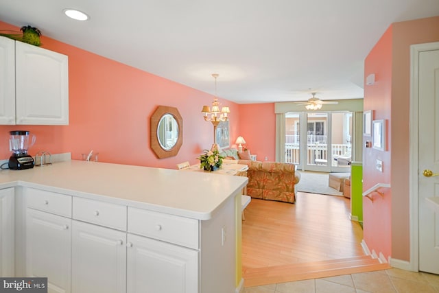 kitchen featuring light tile patterned flooring, a chandelier, hanging light fixtures, kitchen peninsula, and white cabinets