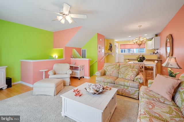 living room featuring ceiling fan with notable chandelier, sink, and light wood-type flooring