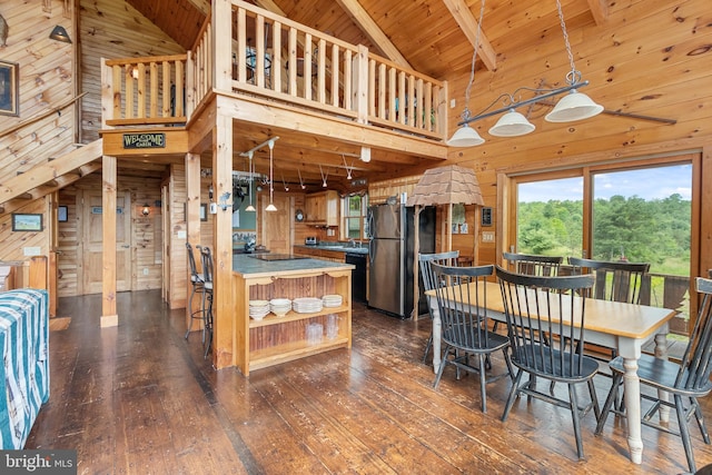 kitchen featuring wood-type flooring, wooden walls, stainless steel refrigerator, and high vaulted ceiling