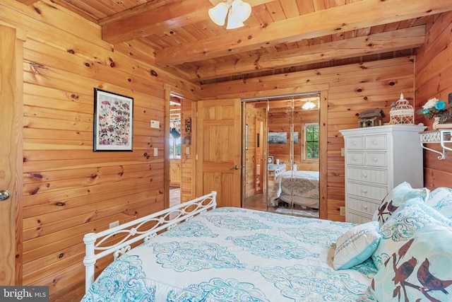 bedroom featuring a closet, wood ceiling, beam ceiling, and wooden walls