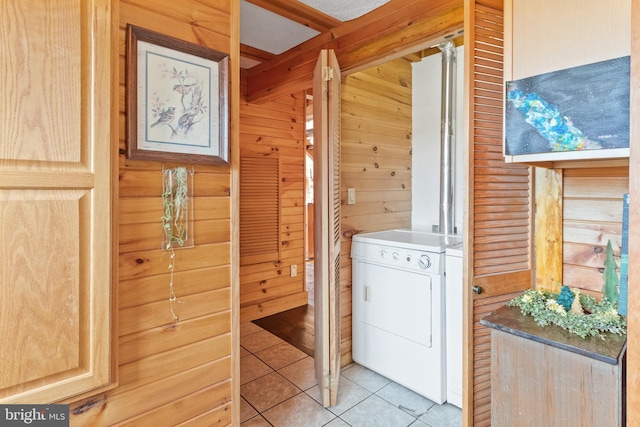 clothes washing area with light tile patterned flooring, washer / dryer, and wooden walls