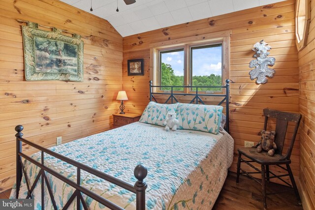 bedroom featuring wooden walls, lofted ceiling, and hardwood / wood-style floors