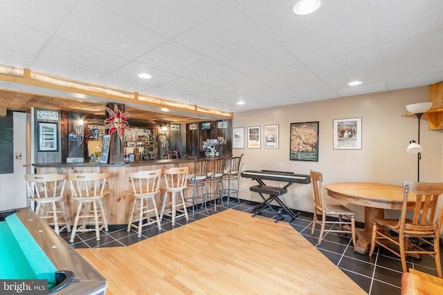 tiled dining area featuring bar area and a drop ceiling